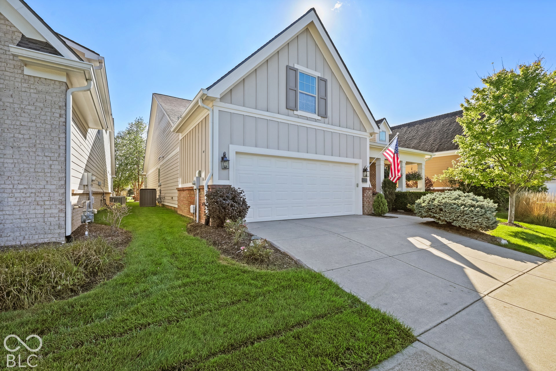 Gabled roofline with vertical siding, brick accents, and a two-car garage