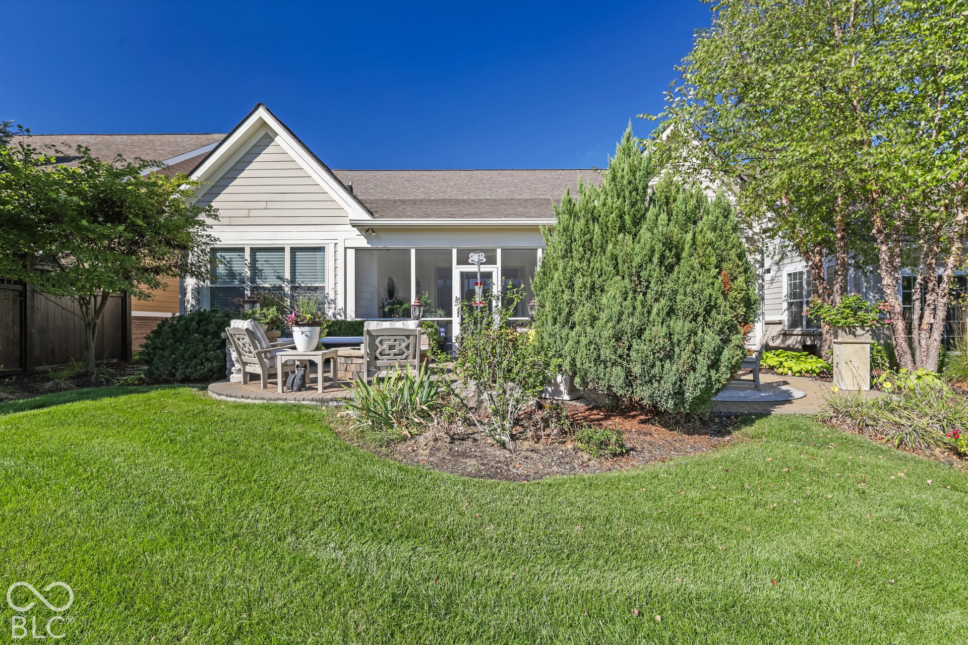 Virtually Altered - Expansive green lawn with mature trees, a screened porch, and a patio area