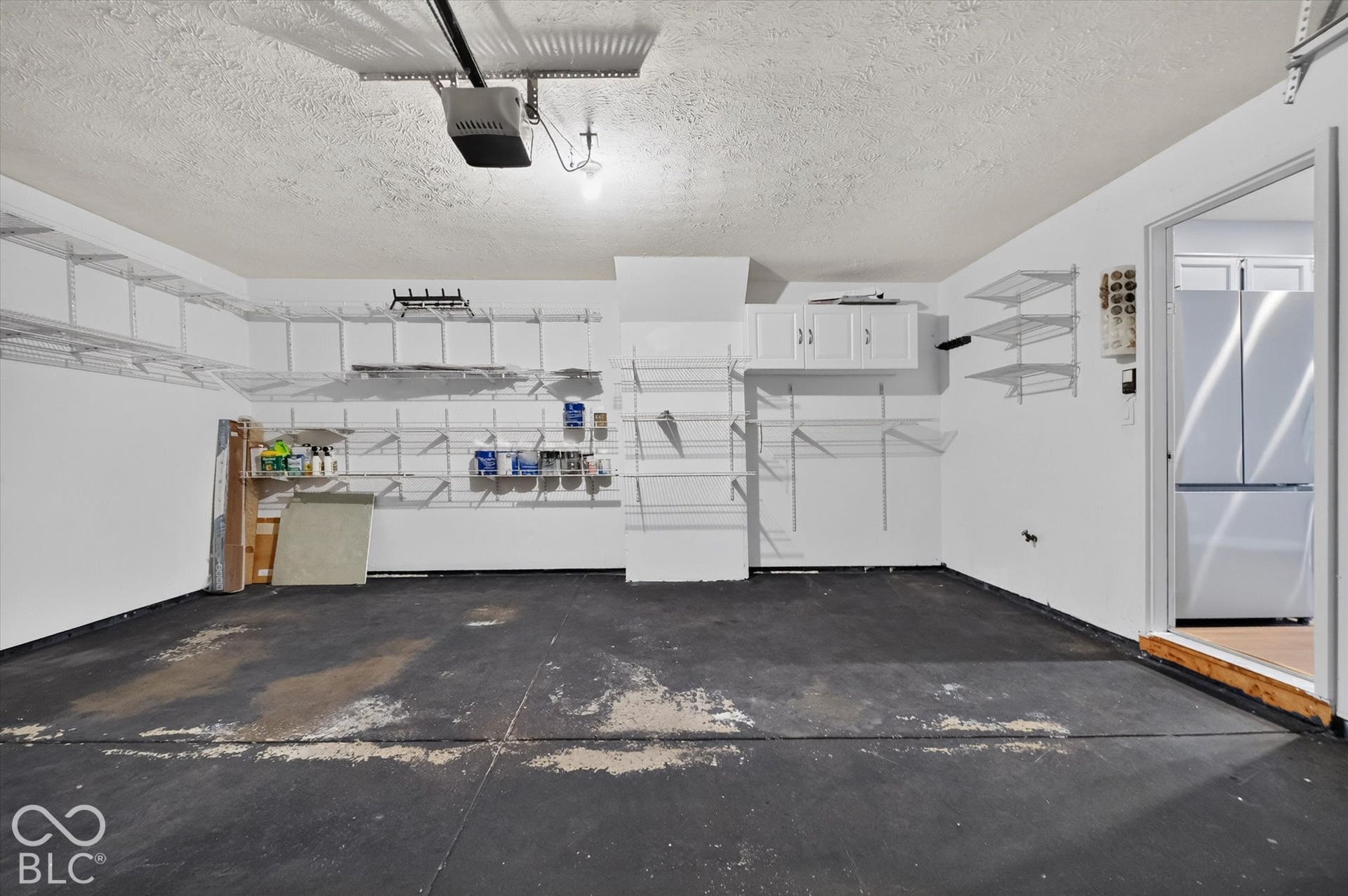 Garage space featuring abundant wall-mounted shelving, built-in overhead cabinets, and a concrete floor