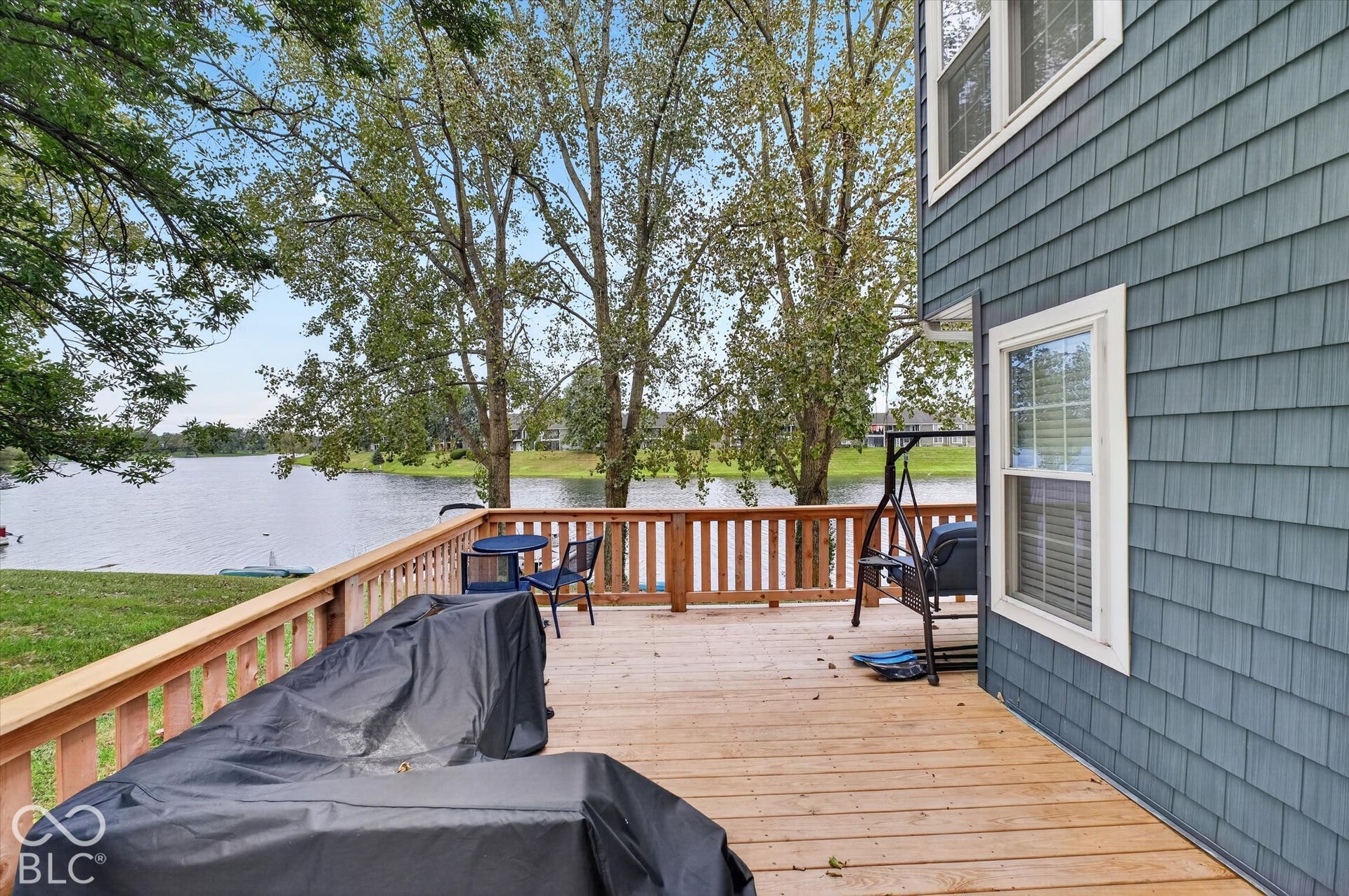 Expansive wood-finish deck with wooden railing overlooking a body of water