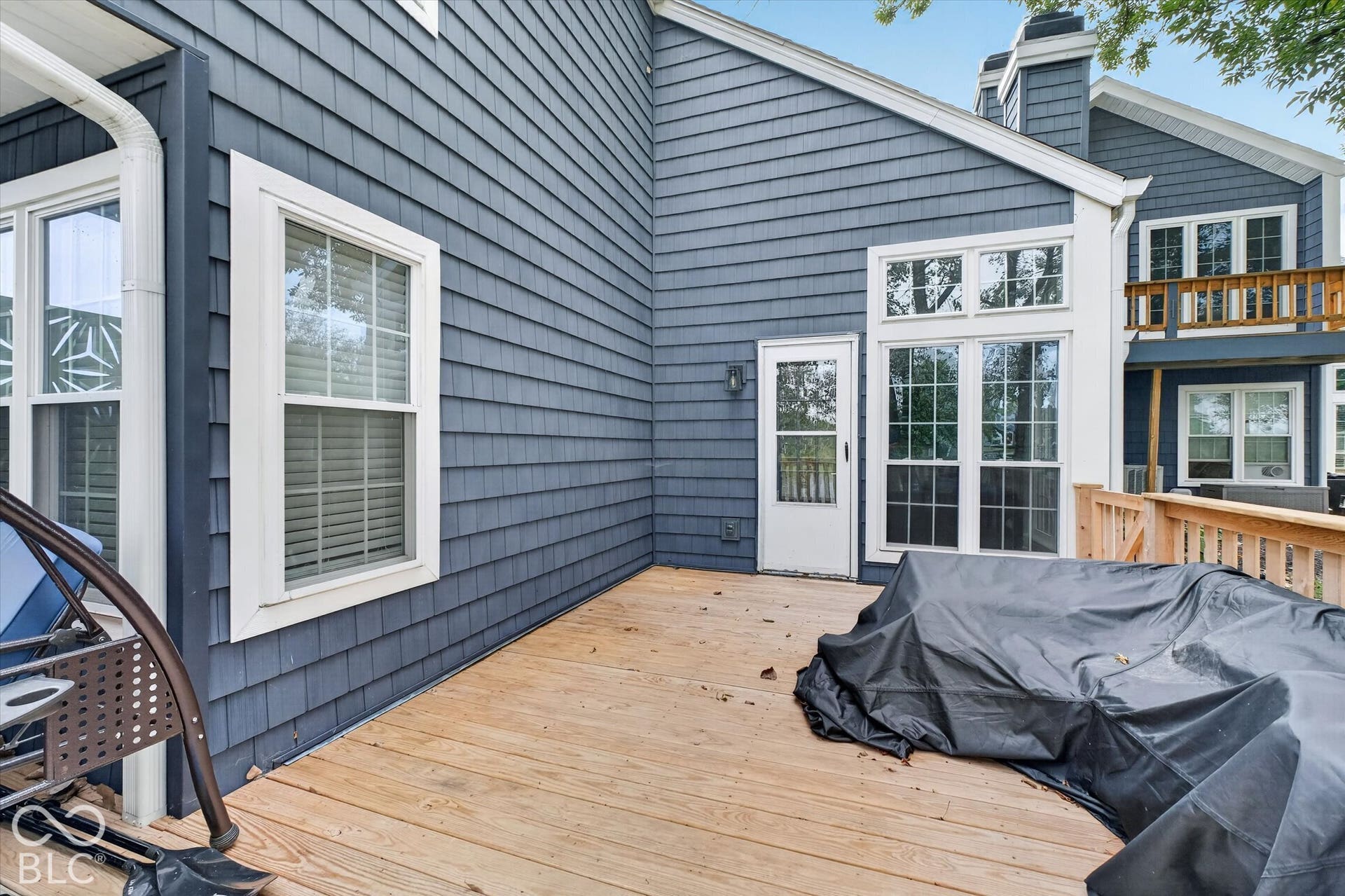 Expansive wood deck with a privacy railing, featuring a shingle-sided exterior and large windows