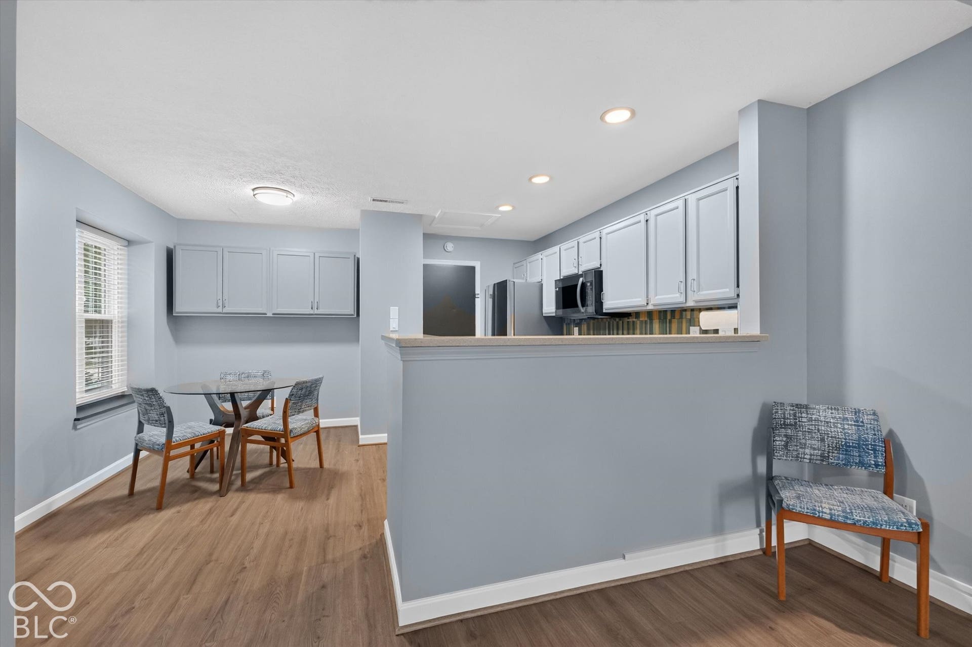 Wood-finish flooring throughout, light gray cabinetry, recessed lighting, built-in microwave, and a pass-through counter