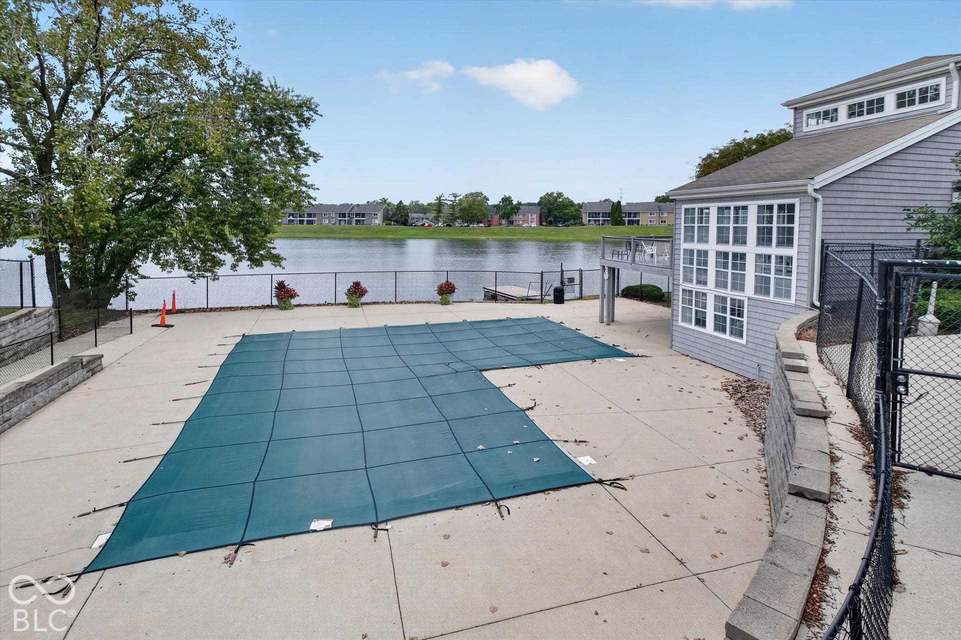 Outdoor swimming pool with a concrete surround, waterfront location, and a multi-windowed sunroom