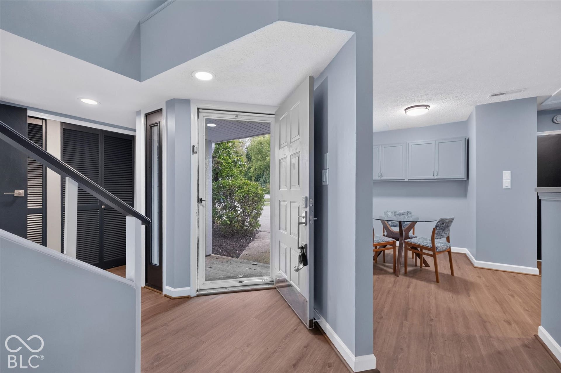 Wood-finish flooring throughout, recessed lighting, and a paneled entry door