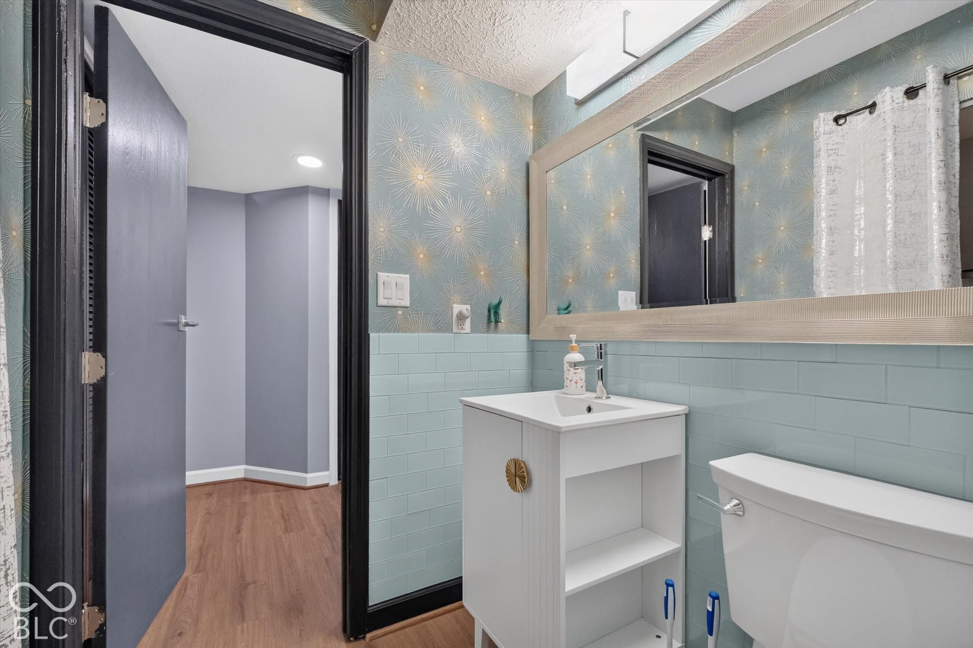 Vanity with undermount sink, a framed mirror, and blue subway tile wainscoting
