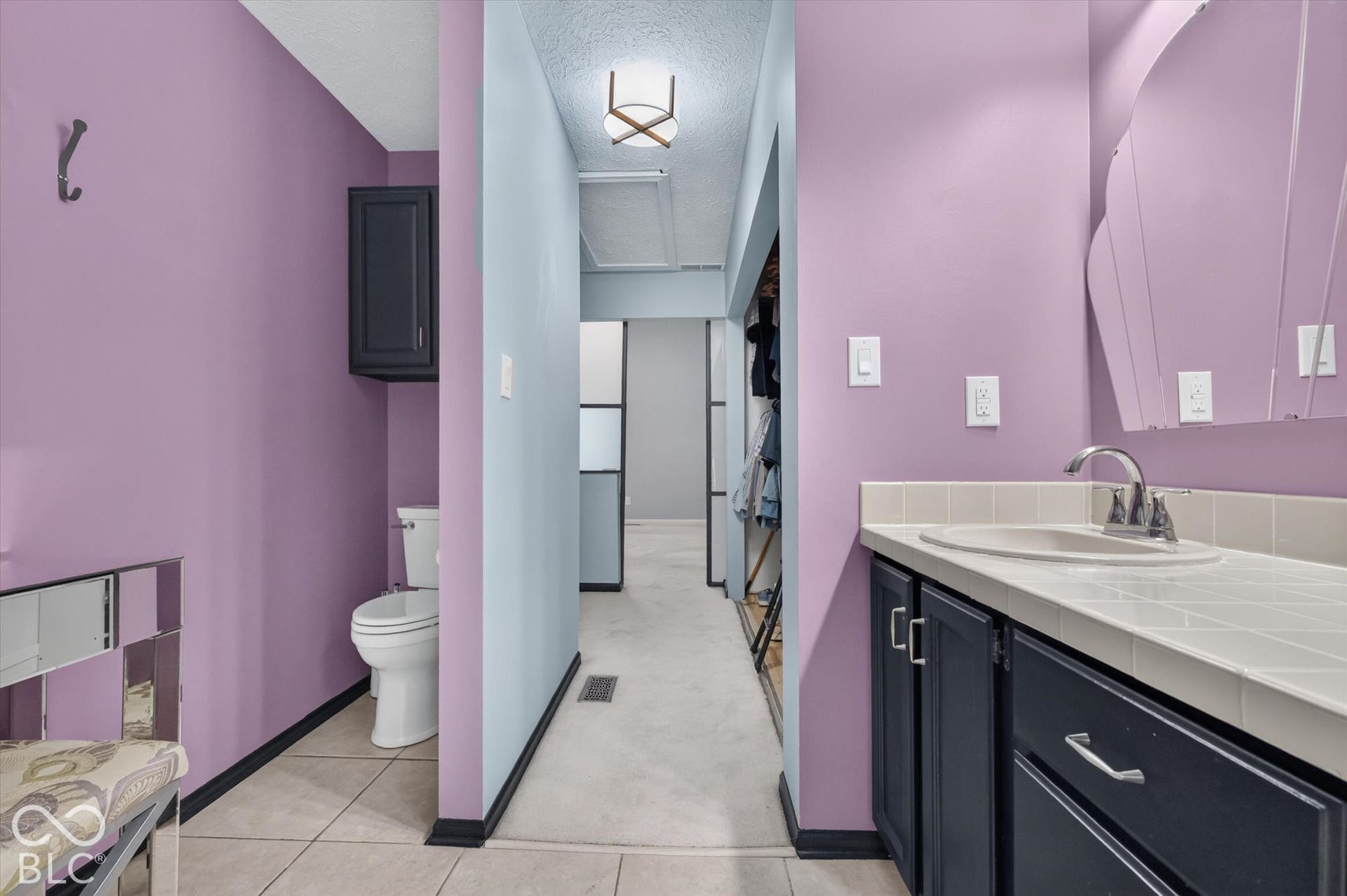 Bathroom featuring a vanity with dark cabinetry, an integrated sink, and a tiled countertop