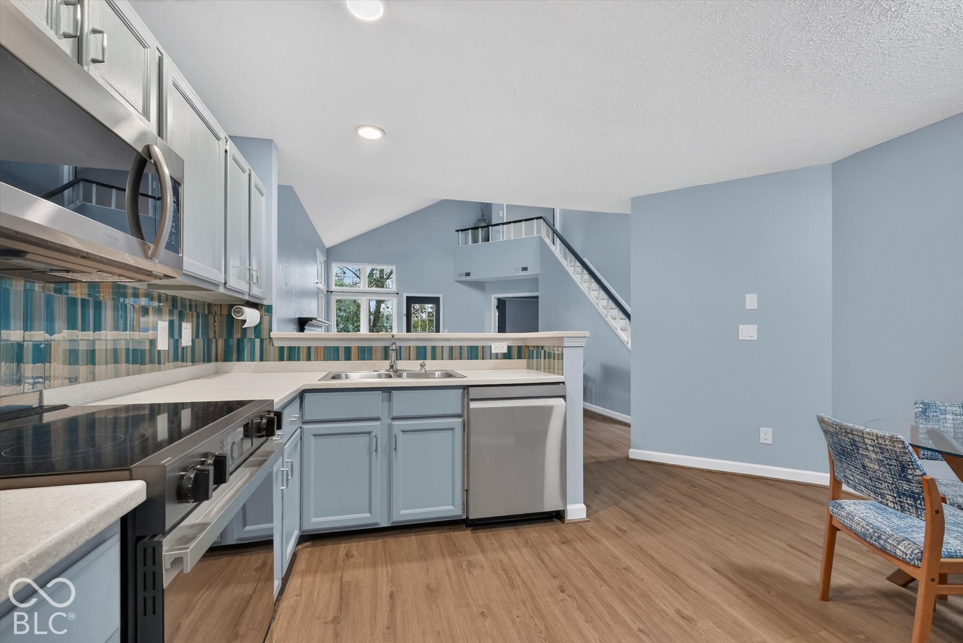 Kitchen featuring stainless steel appliances, light-toned cabinetry, light-colored countertops, and a decorative tile backsplash