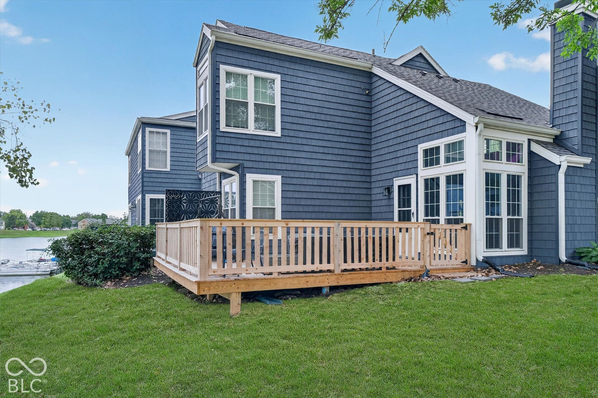 Rear exterior featuring blue shake siding, a wooden deck with railing, and a bay window