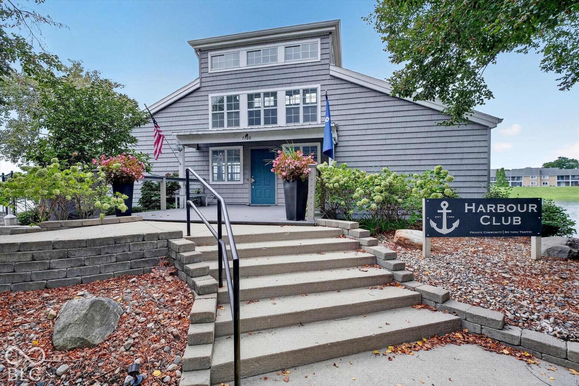 Multi-level concrete stairs with black metal handrails lead to a covered entry with a vibrant blue door