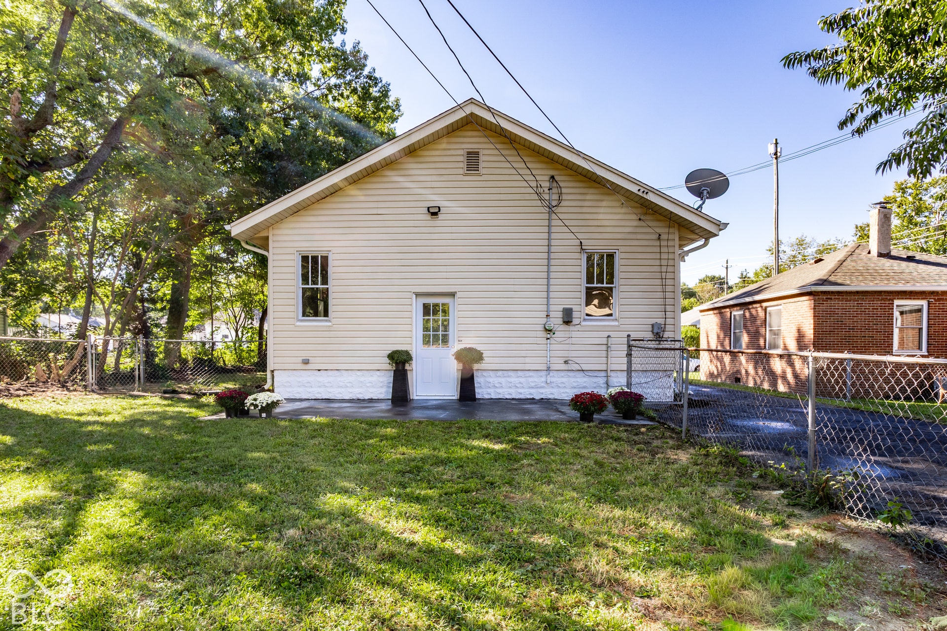 Rear exterior featuring light-colored siding, a gabled roof, and a white entry door
