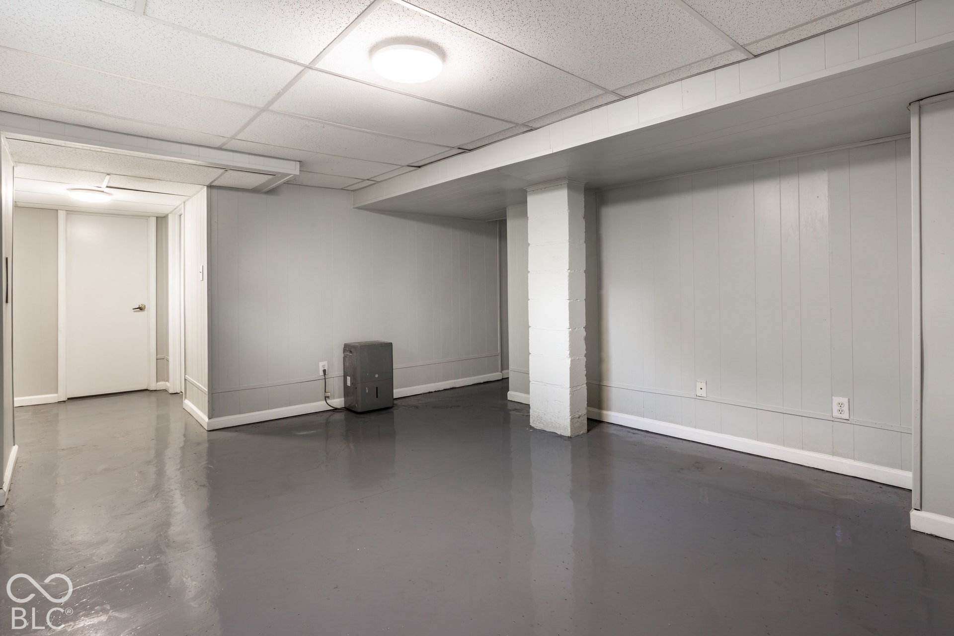 Smooth gray flooring, light gray paneled walls, white ceiling tiles, and flush-mount lighting fixtures
