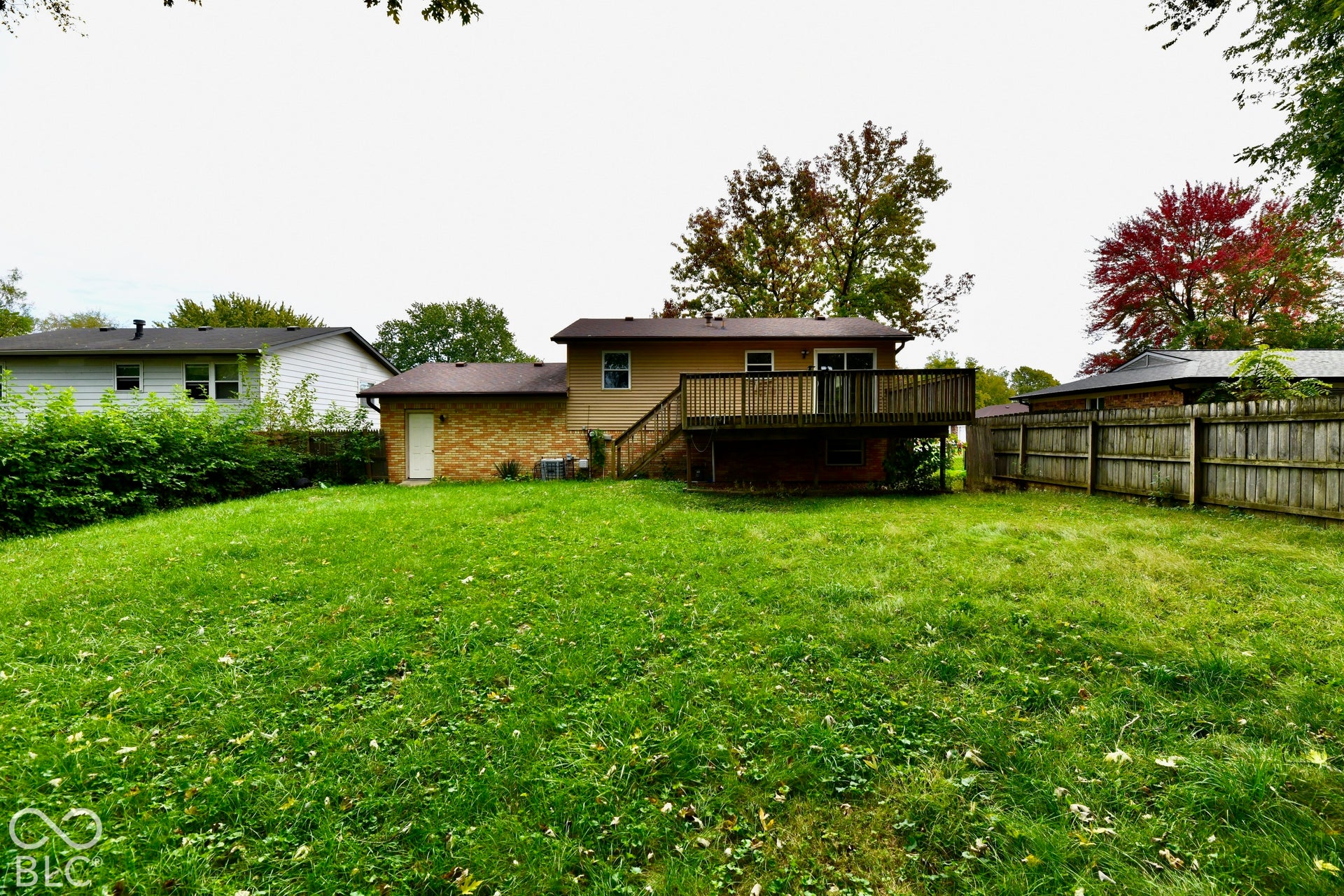 Expansive grassy yard with a multi-level wood deck and a brick exterior addition