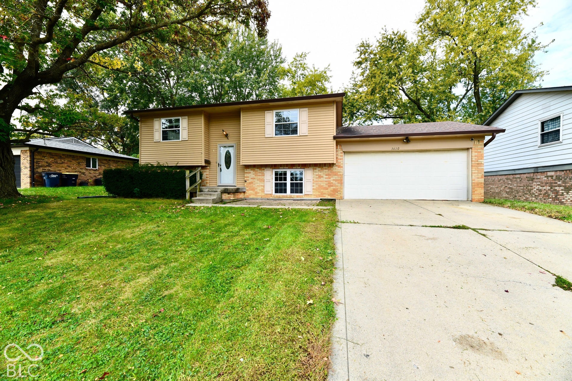 Split-level residence featuring a two-car garage, concrete driveway, and front lawn