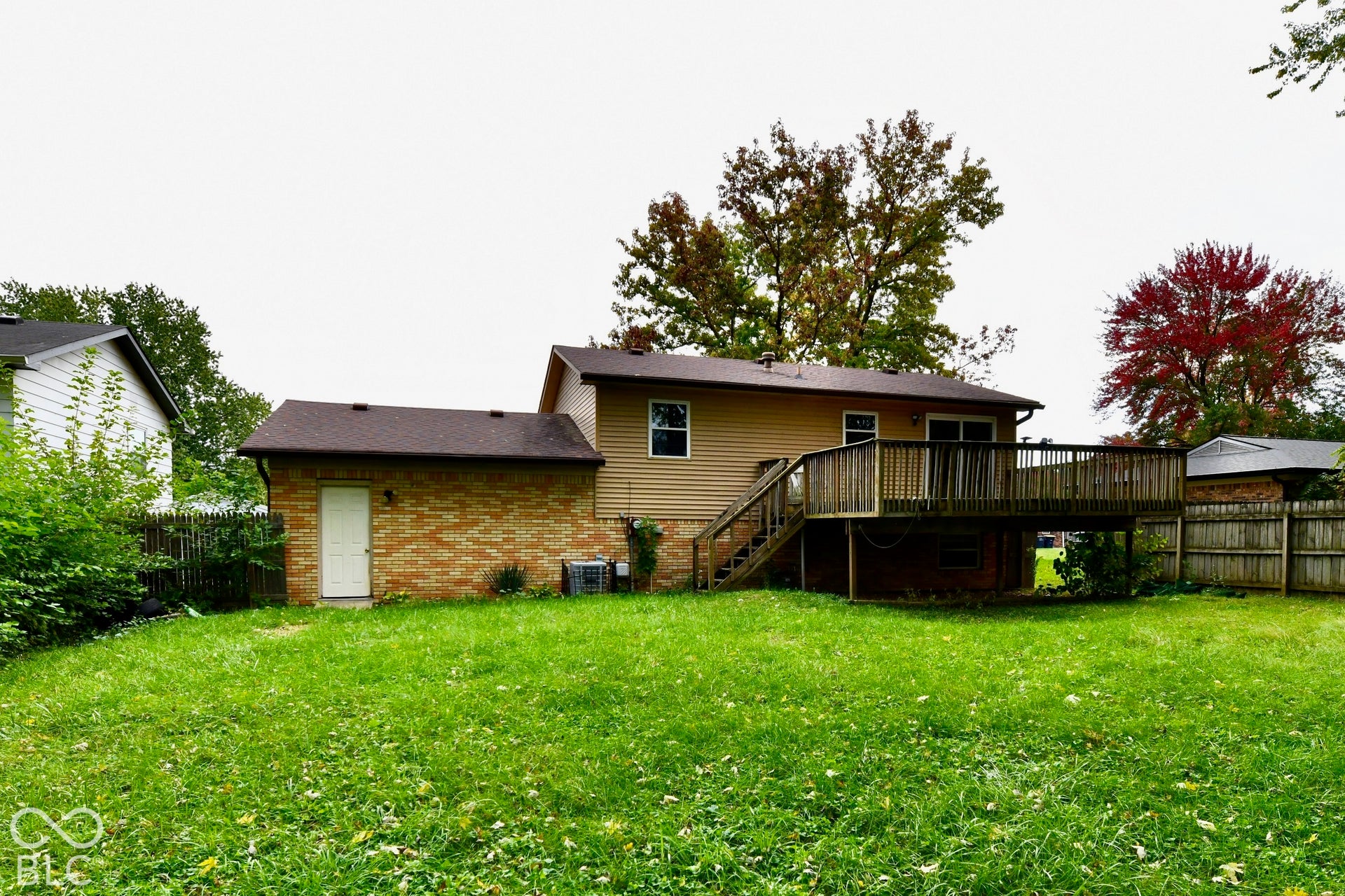 Expansive backyard with a wooden deck, brick and siding exterior, and a detached brick structure