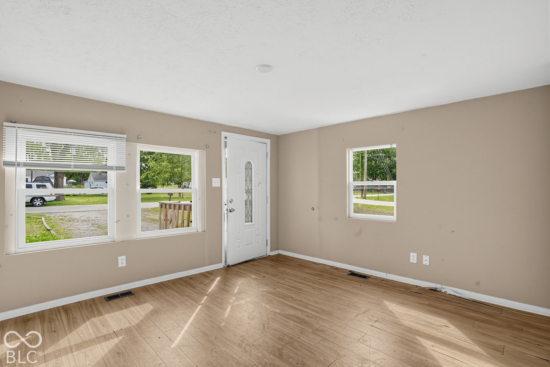 3128 S Rural Street, Indianapolis, IN 46237 Wood-finish flooring, multiple windows providing ambient light, and a white entry door with decorative glass inlay