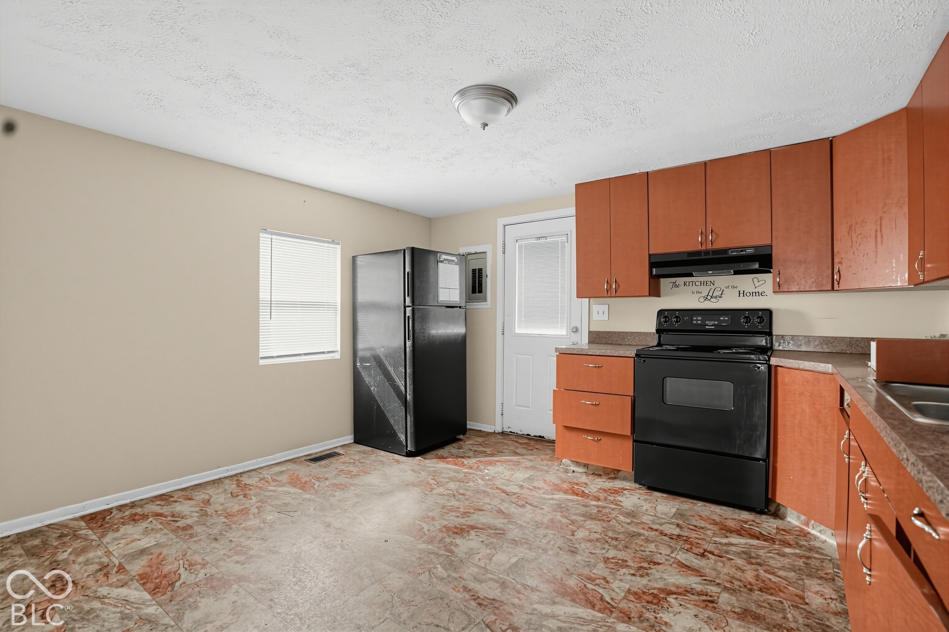 3128 S Rural Street, Indianapolis, IN 46237 Functional kitchen featuring wood-finish cabinetry, dark countertop surfaces, a black range, and a black refrigerator