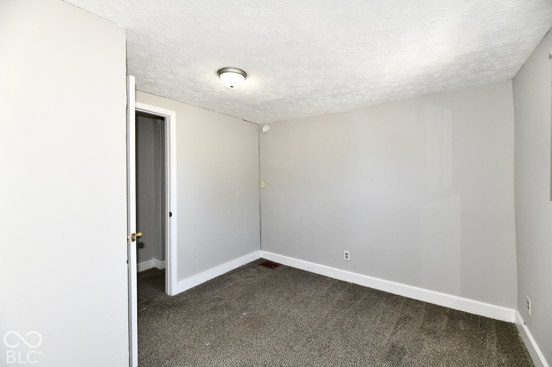 Neutral wall color, textured ceiling, carpeted flooring, and a flush mount light fixture