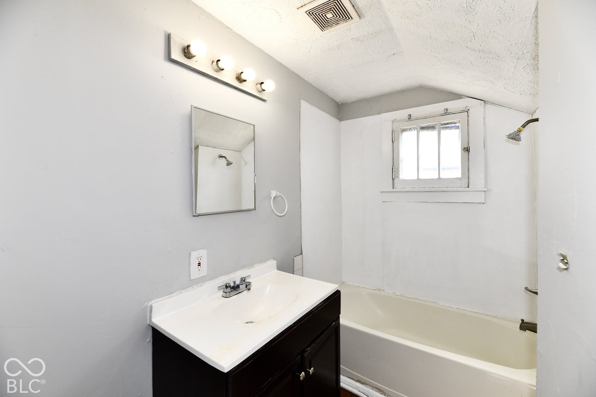 White vanity with integrated sink, chrome faucet, and mirrored cabinet