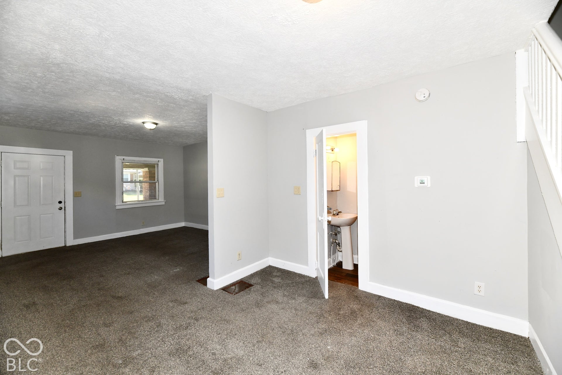Neutral wall paint, carpet flooring, interior door, window with exterior brick detail, and visible staircase