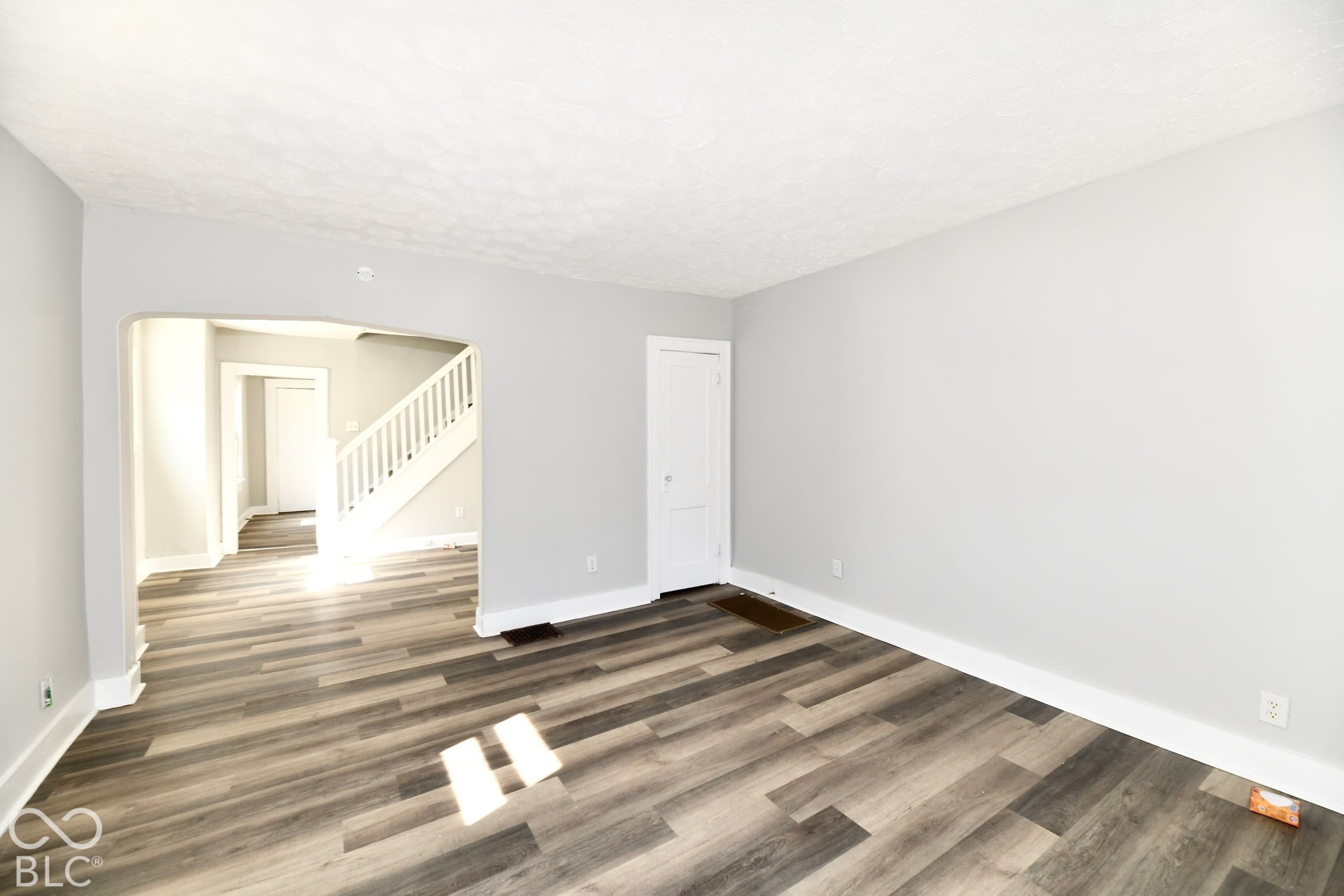 Light gray wall finishes, wood-finish flooring, white trim, and a white staircase with balusters