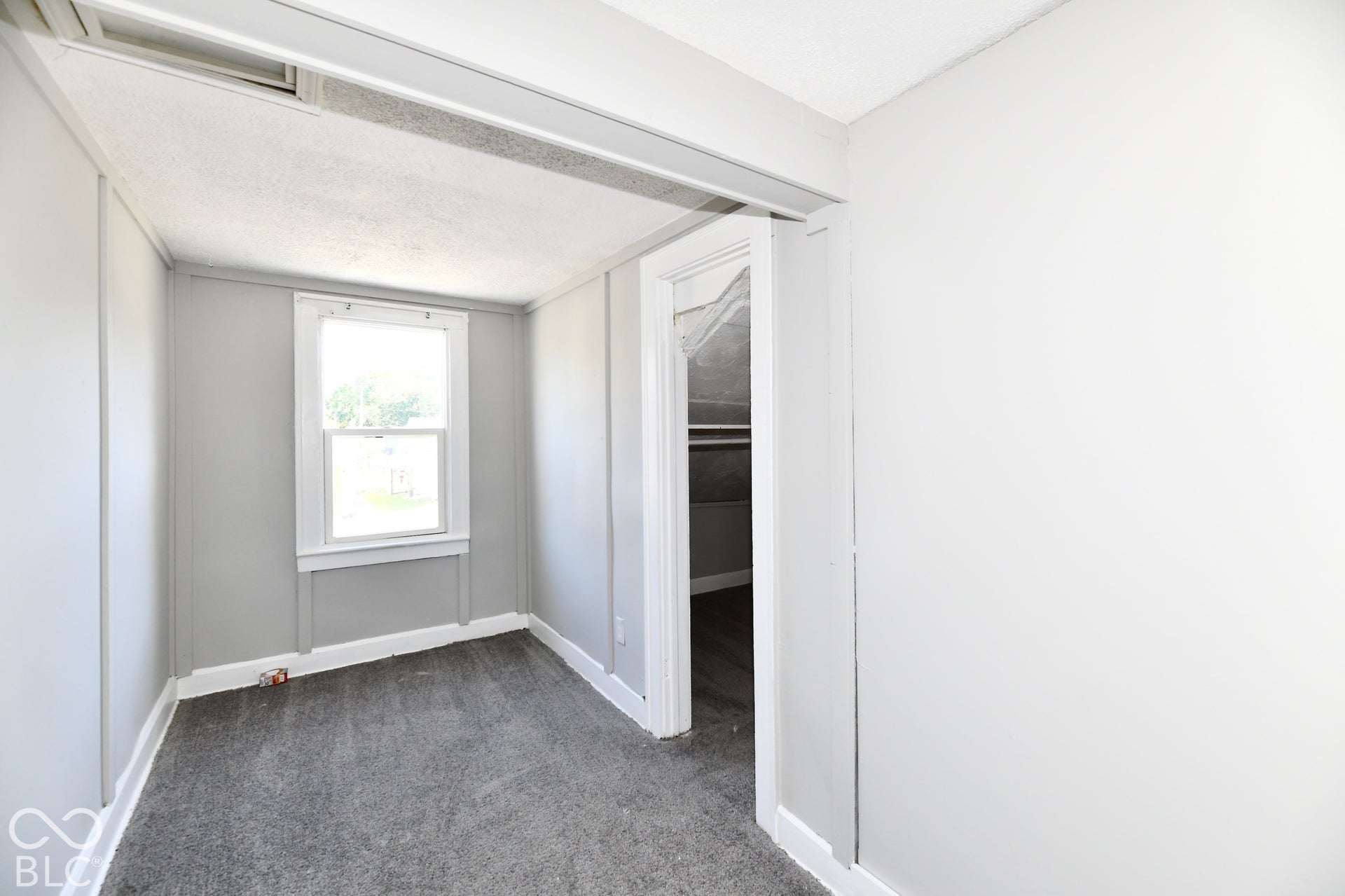 Recessed window, gray wall paneling, white trim, textured ceiling, and gray carpet