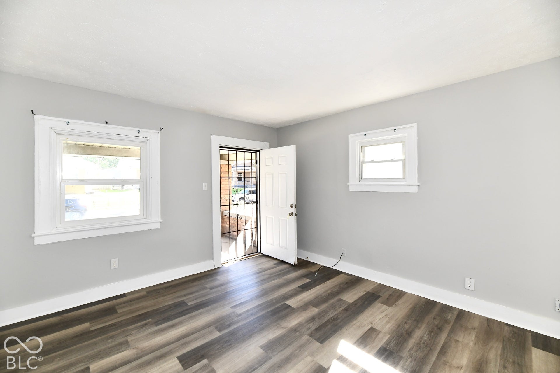 Wood-finish flooring, light gray walls, white trim, and white window frames