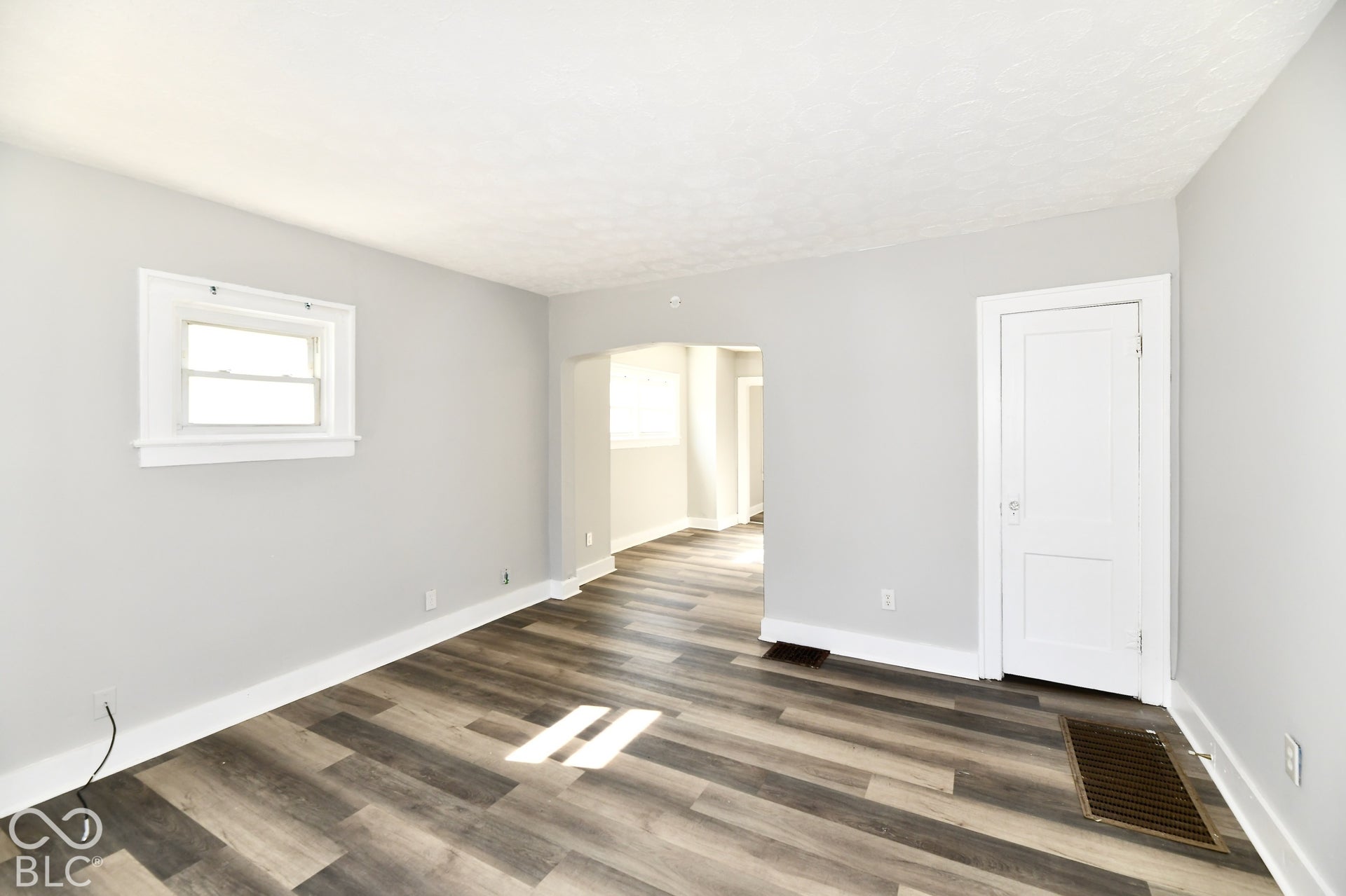 Light gray painted walls, wood-finish flooring, white window trim, and white baseboards