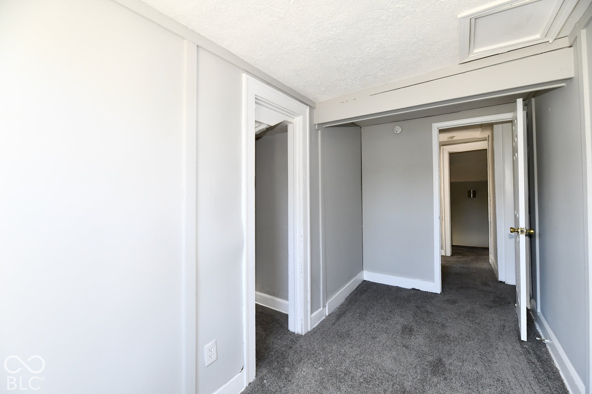 Textured ceiling, painted trim, neutral wall tones, and carpeted flooring