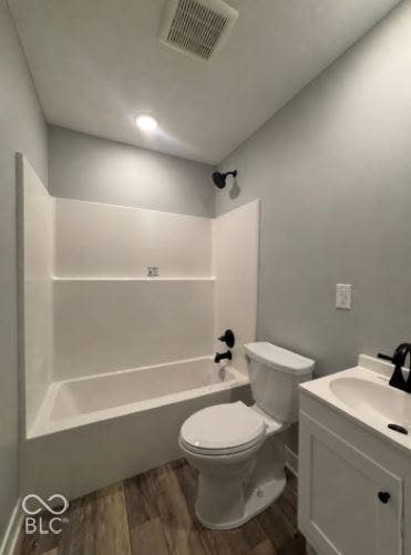 252 Indiana Street, Plainfield, IN 46168 Tub/shower combination with black fixtures, toilet, single vanity with integrated sink, and wood-finish flooring