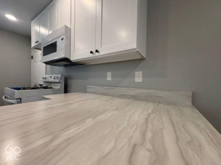 252 Indiana Street, Plainfield, IN 46168 White shaker cabinetry, over-the-range microwave, electric range, and light-toned countertops with an integrated backsplash