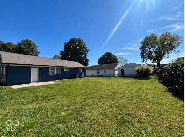 252 Indiana Street, Plainfield, IN 46168 Expansive backyard featuring a concrete patio, blue siding, a white door, and white-framed windows