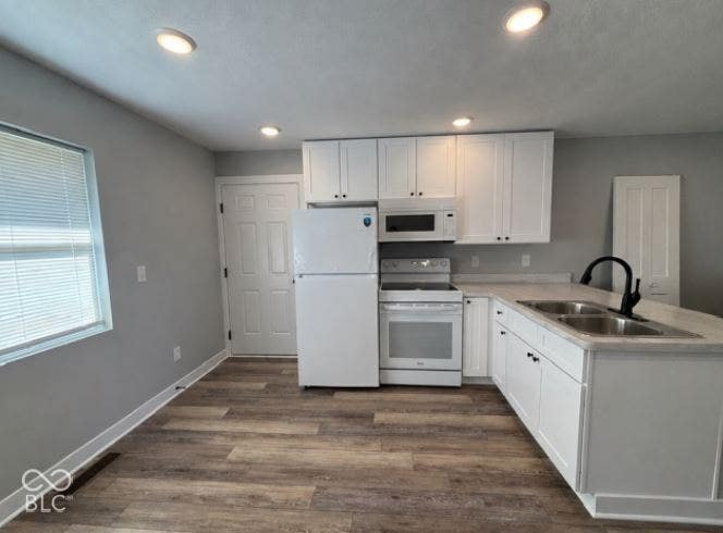 252 Indiana Street, Plainfield, IN 46168 Kitchen featuring white cabinetry, white appliances, a double basin stainless steel sink with a black gooseneck faucet, light-toned countertops, and wood-finish flooring