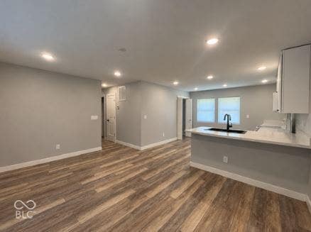 252 Indiana Street, Plainfield, IN 46168 Wood-finish flooring, recessed lighting, neutral gray wall tones, a kitchen island with a black sink and faucet, and white cabinetry