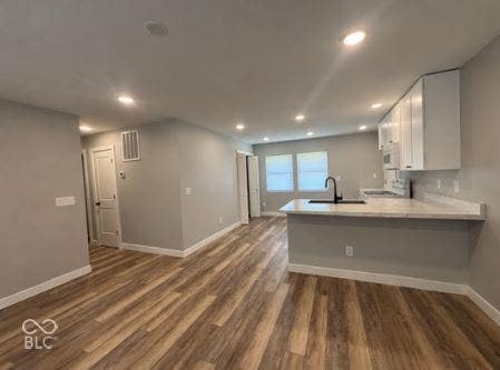 252 Indiana Street, Plainfield, IN 46168 Wood-finish flooring, recessed lighting, white kitchen cabinetry, a kitchen island with a countertop, and a black gooseneck faucet