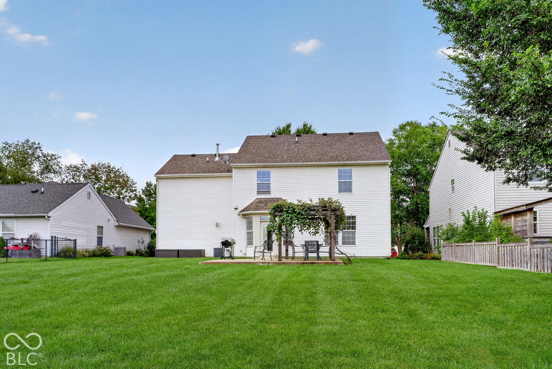 15996 Arbor Grove Boulevard, Noblesville, IN 46060 Expansive green lawn, white vinyl siding, brown shingle roof, concrete patio, and a wood pergola