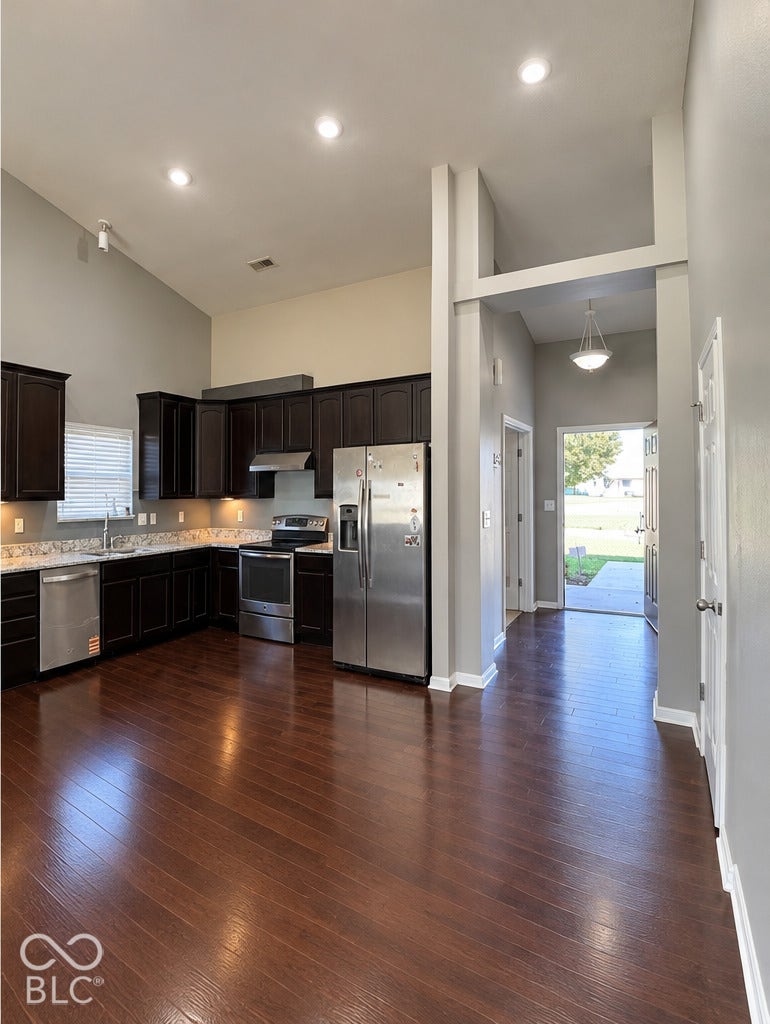 4348 Big Leaf Lane, Indianapolis, IN 46239 Kitchen featuring dark wood cabinetry, stainless steel appliances, wood-finish flooring, and vaulted ceilings with recessed lighting