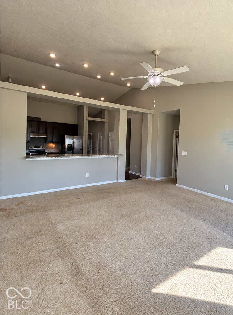 4348 Big Leaf Lane, Indianapolis, IN 46239 Vaulted ceiling with recessed lighting and a ceiling fan, featuring a kitchen peninsula with a light-toned countertop and dark wood-finish cabinetry