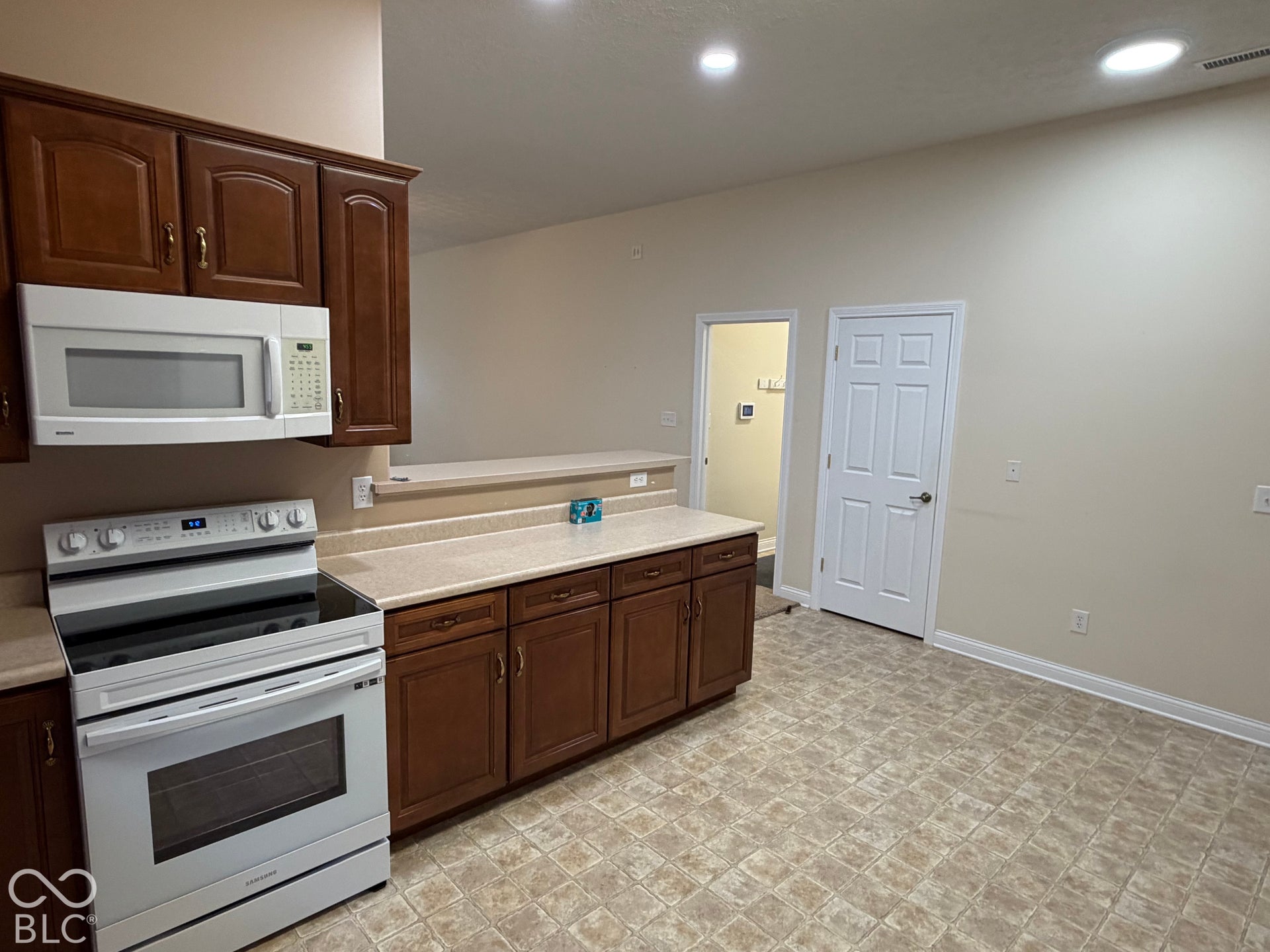 Kitchen featuring wood-finish cabinetry, solid surface countertops, white range, and built-in microwave