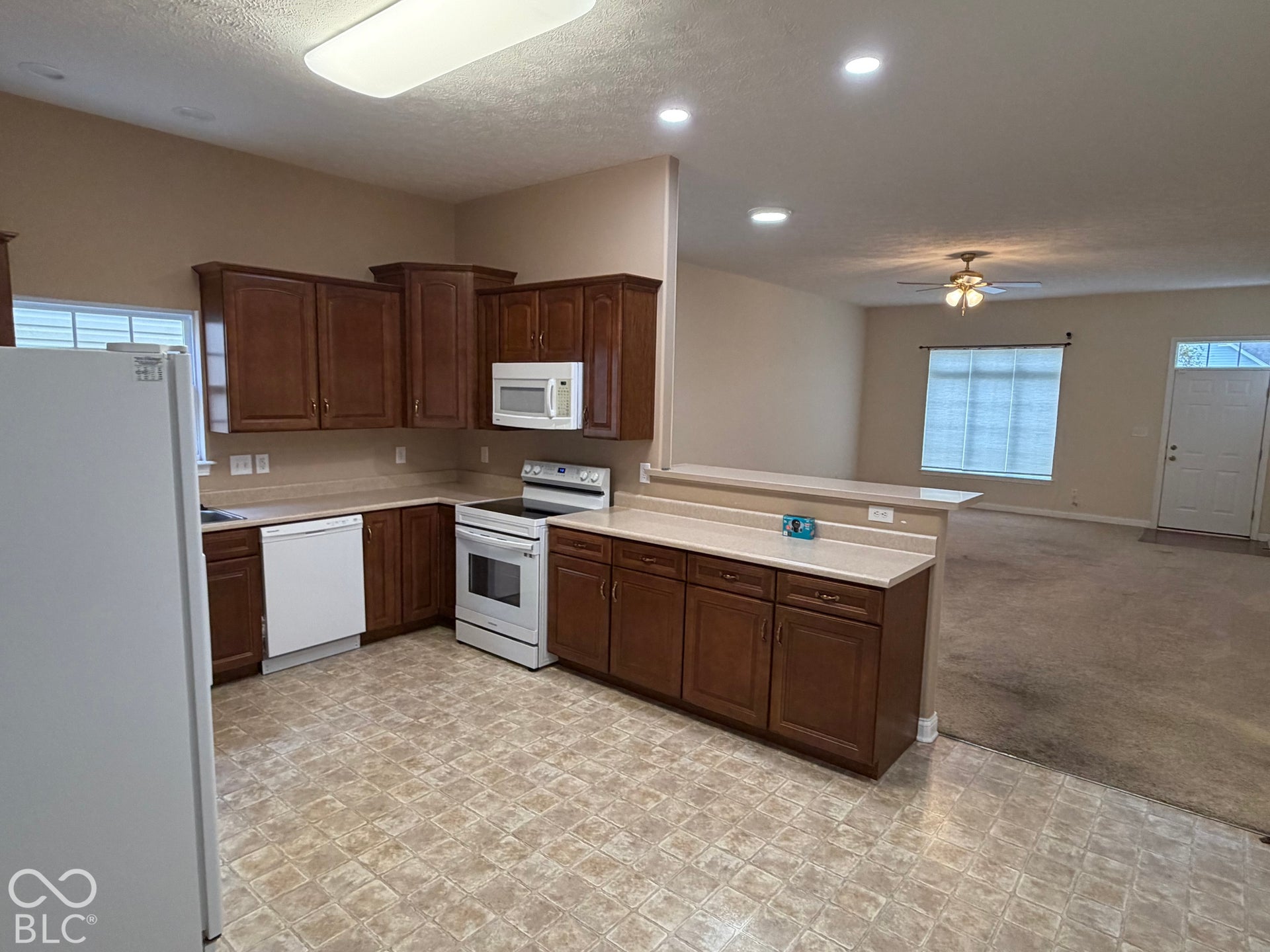 Kitchen featuring wood-finish cabinetry, white appliances, and a pass-through counter