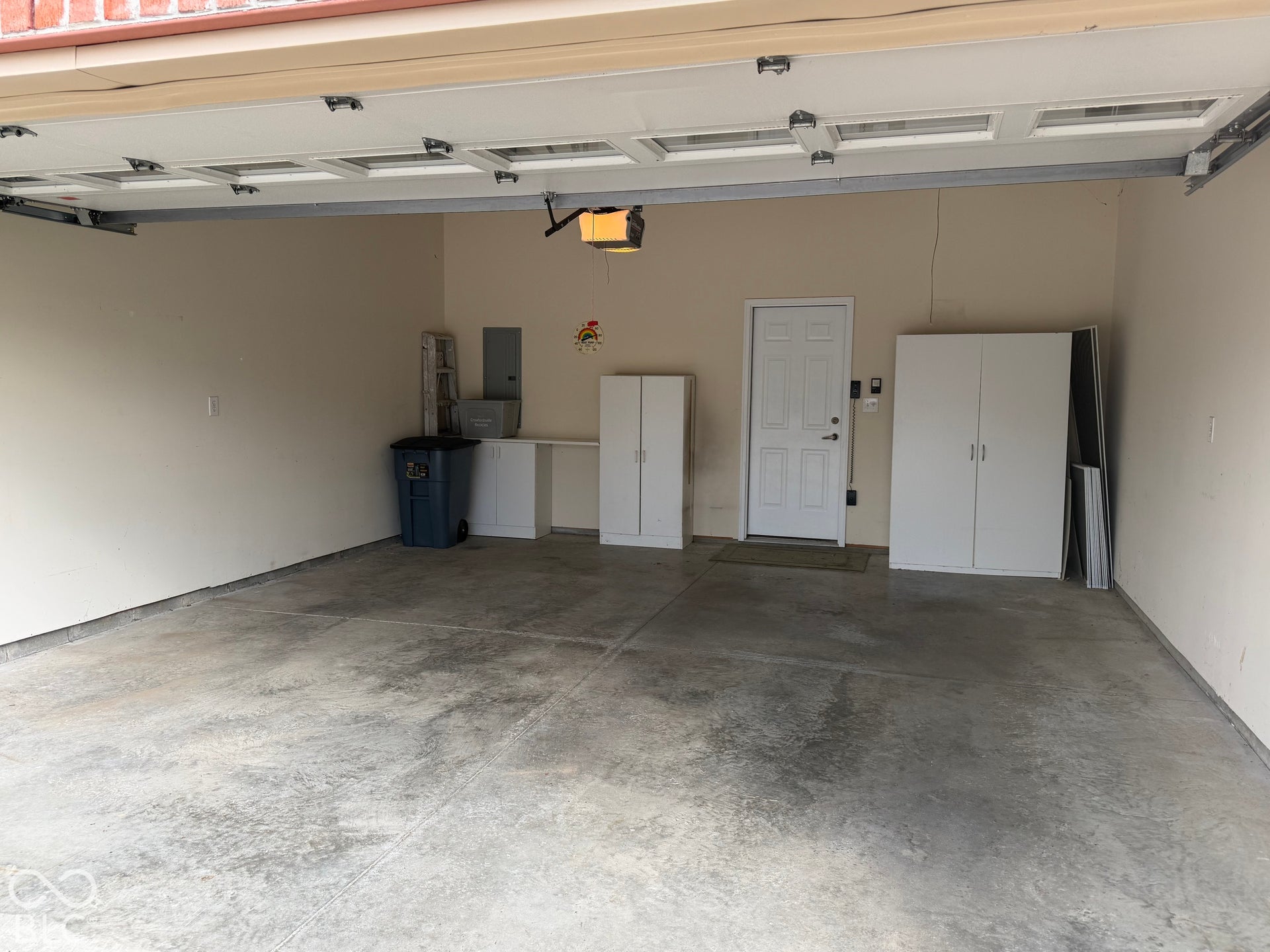 Attached garage with light-toned walls, concrete flooring, and an overhead garage door
