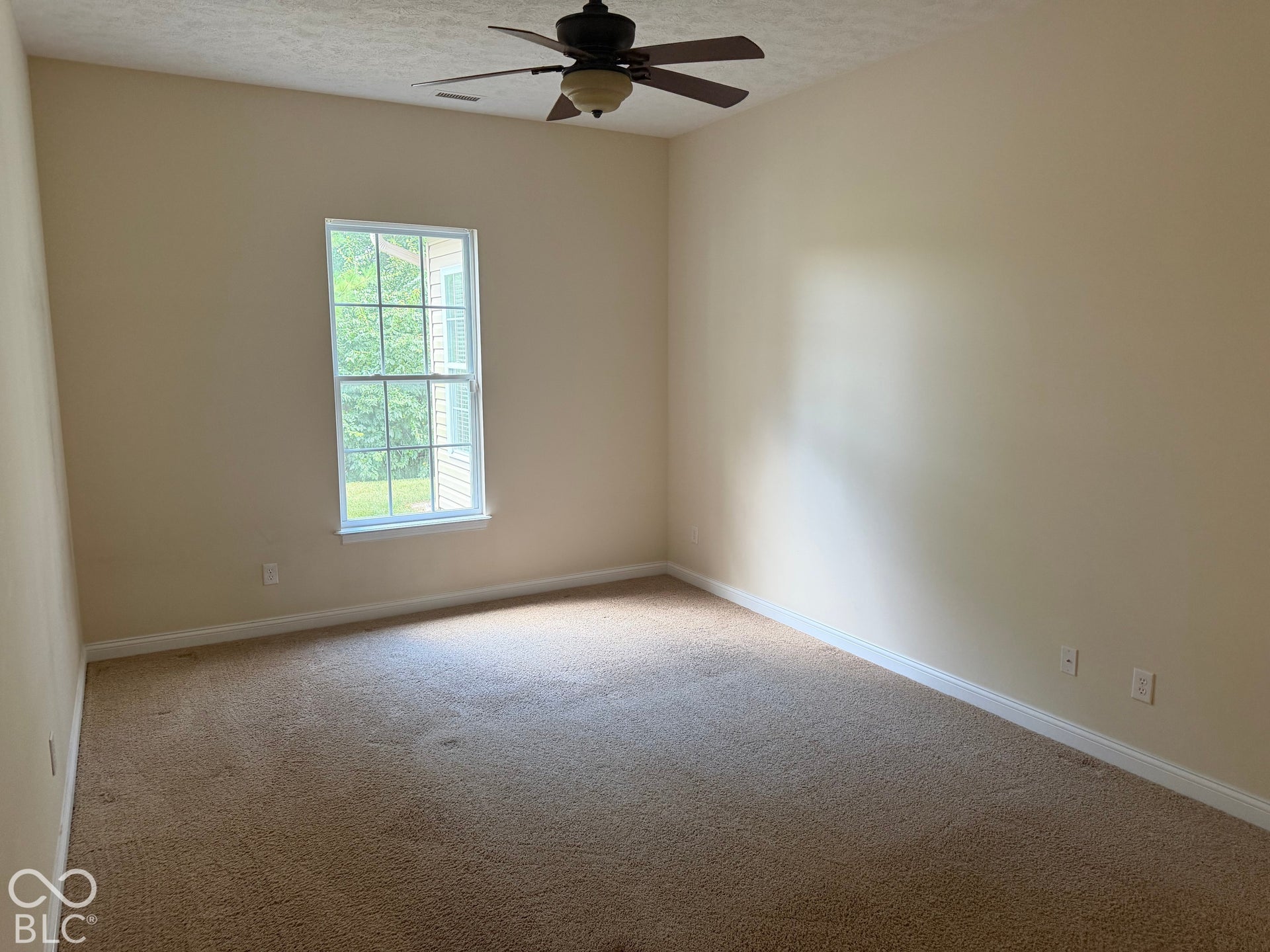 Neutral wall color, carpeted flooring, window with white trim, and ceiling fan with integrated lighting