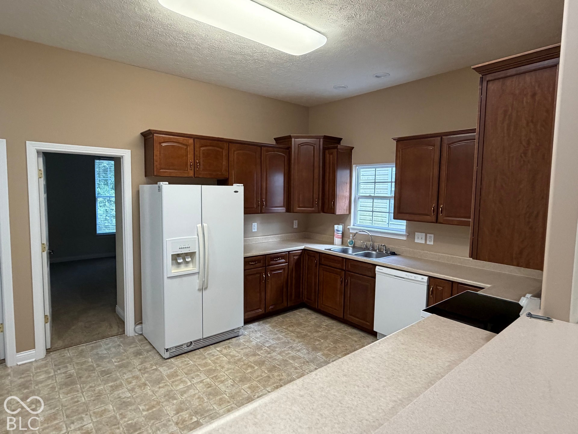 Kitchen featuring wood-finish cabinetry, light-toned countertops, and an integrated double basin sink