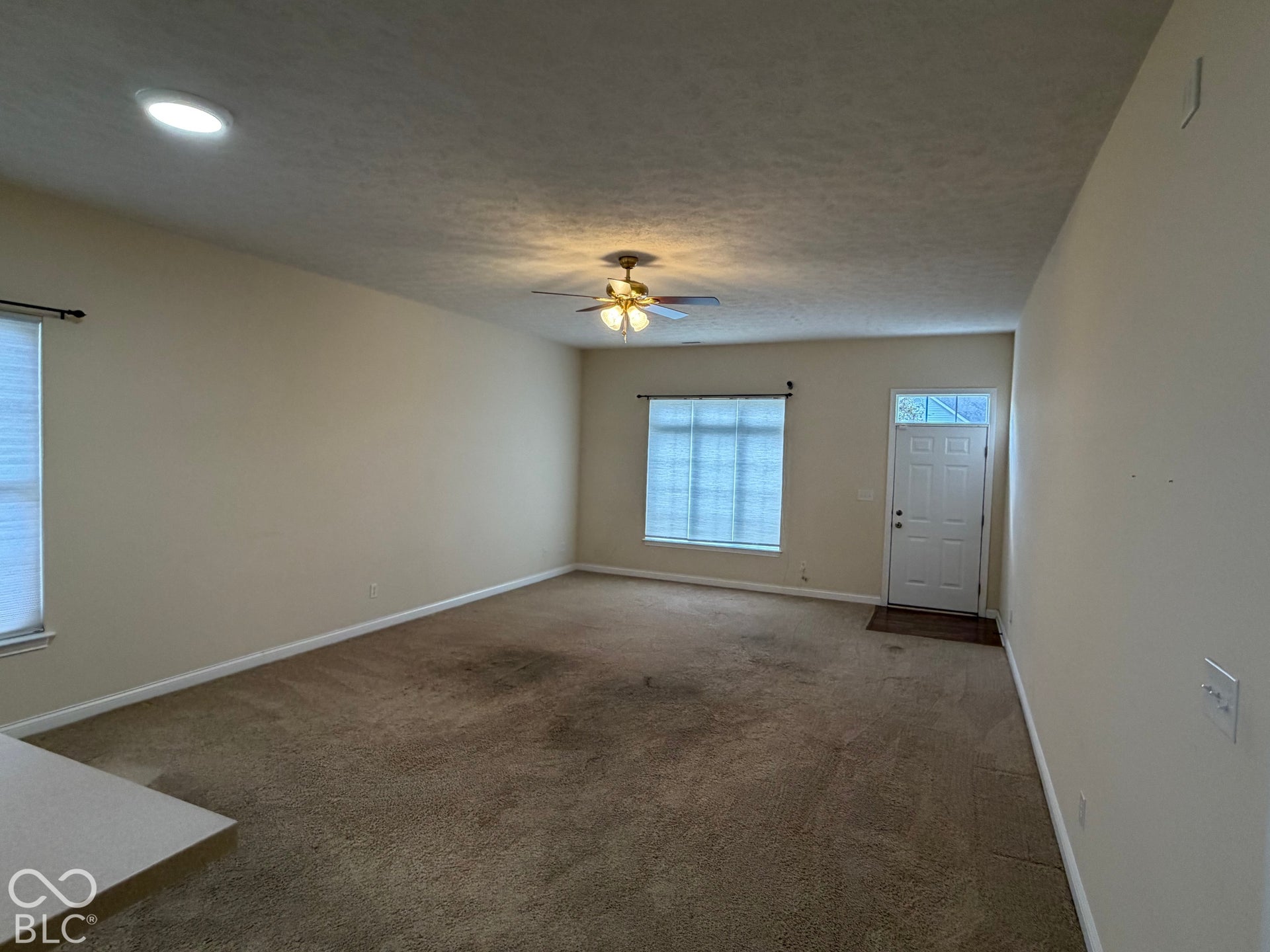 Recessed ceiling lighting, ceiling fan light fixture, front door with transom window, and windows with blinds