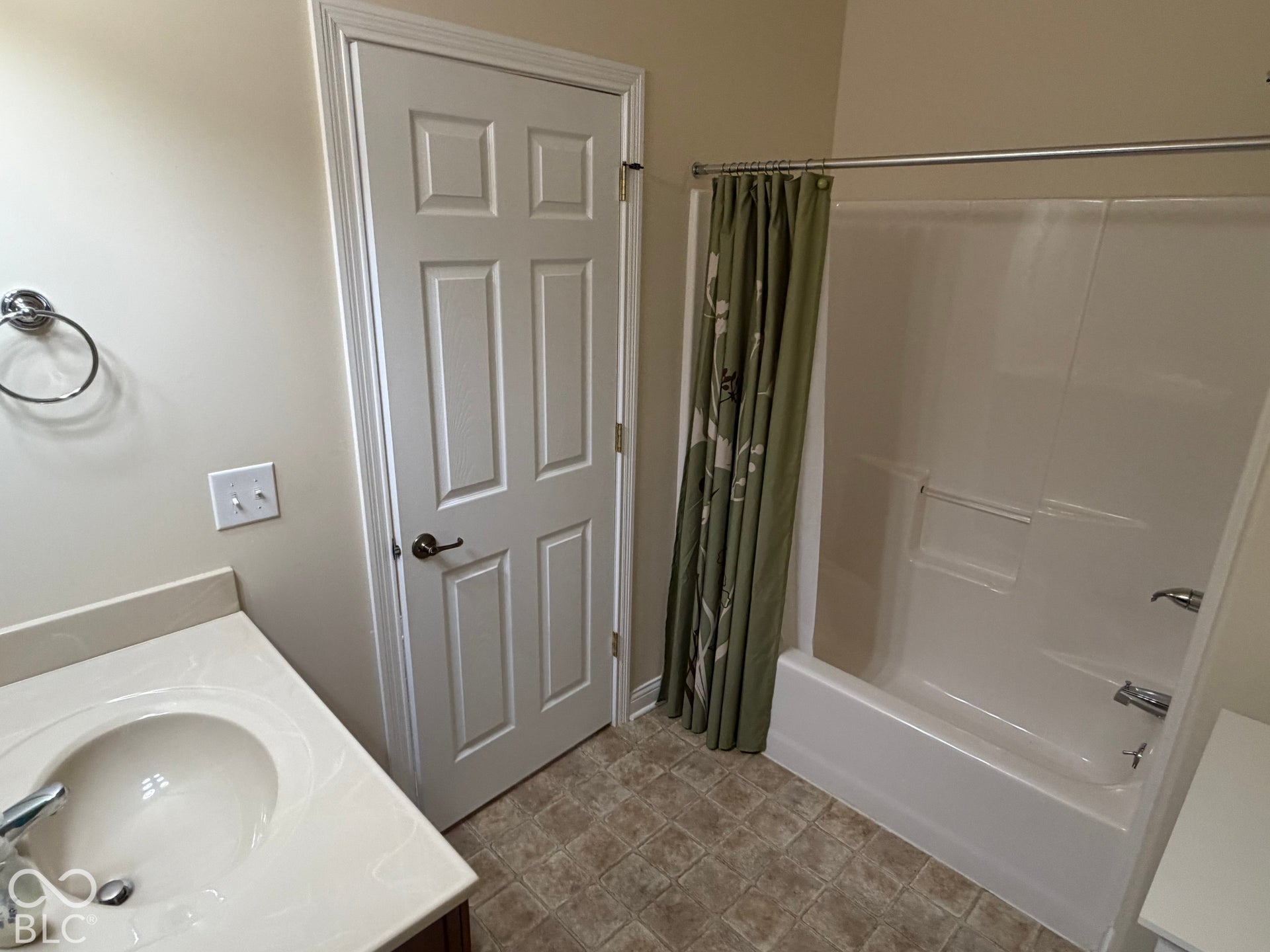 Bathroom featuring a single vanity with an integrated sink, a white panel door, and a white tub/shower combination