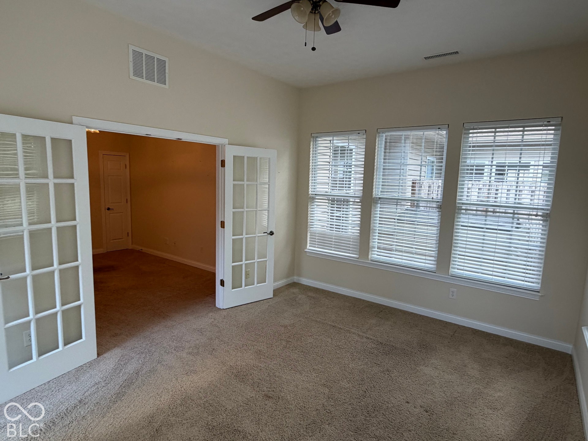 Triple windows with white blinds, vaulted ceiling, ceiling fan, and French doors