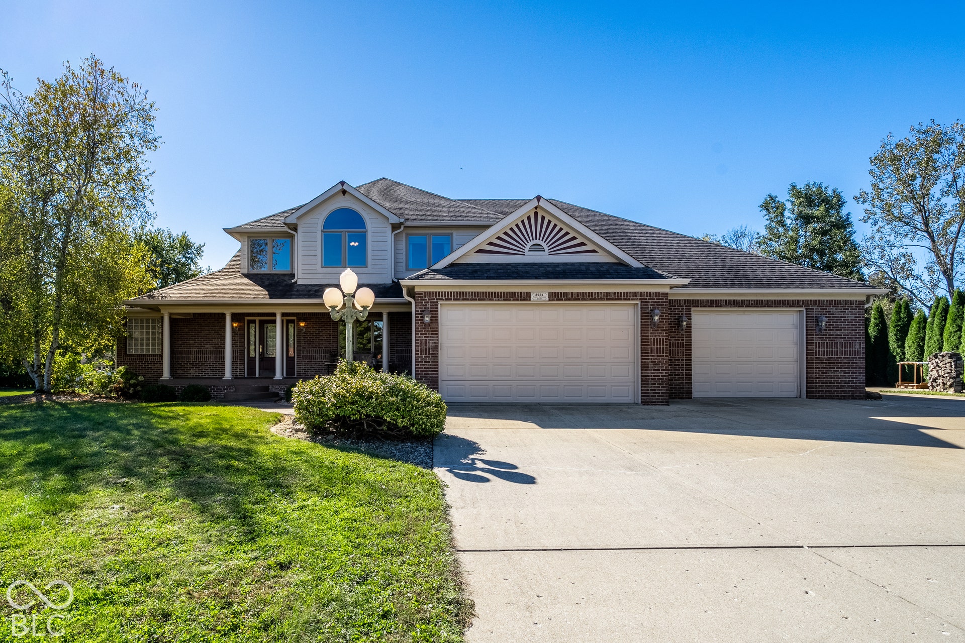 Brick exterior featuring a covered porch, four-car garage