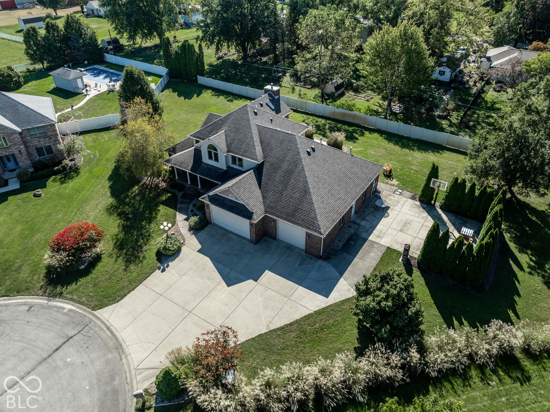 Brick exterior with an attached four-car garage, concrete driveway, and a covered front porch