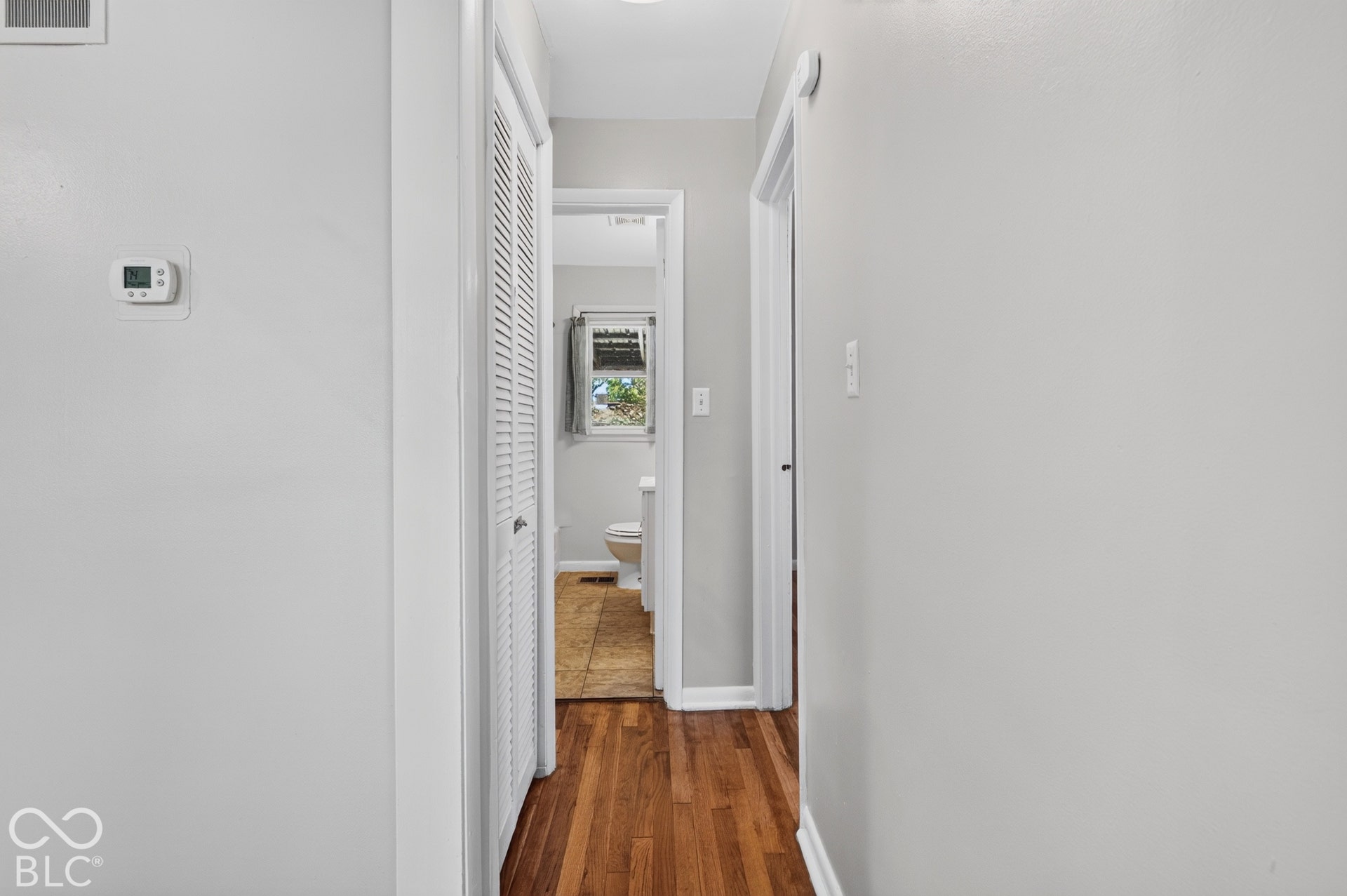 2706 13th Street, Columbus, IN 47201 Hallway featuring wood-finish flooring, white louvered closet doors, and neutral wall paint