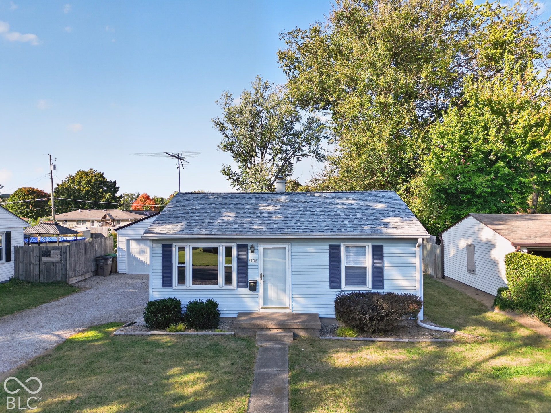 2706 13th Street, Columbus, IN 47201 Single-story residence featuring light blue horizontal siding, dark shutters, a bay window, asphalt shingle roof, and a detached garage