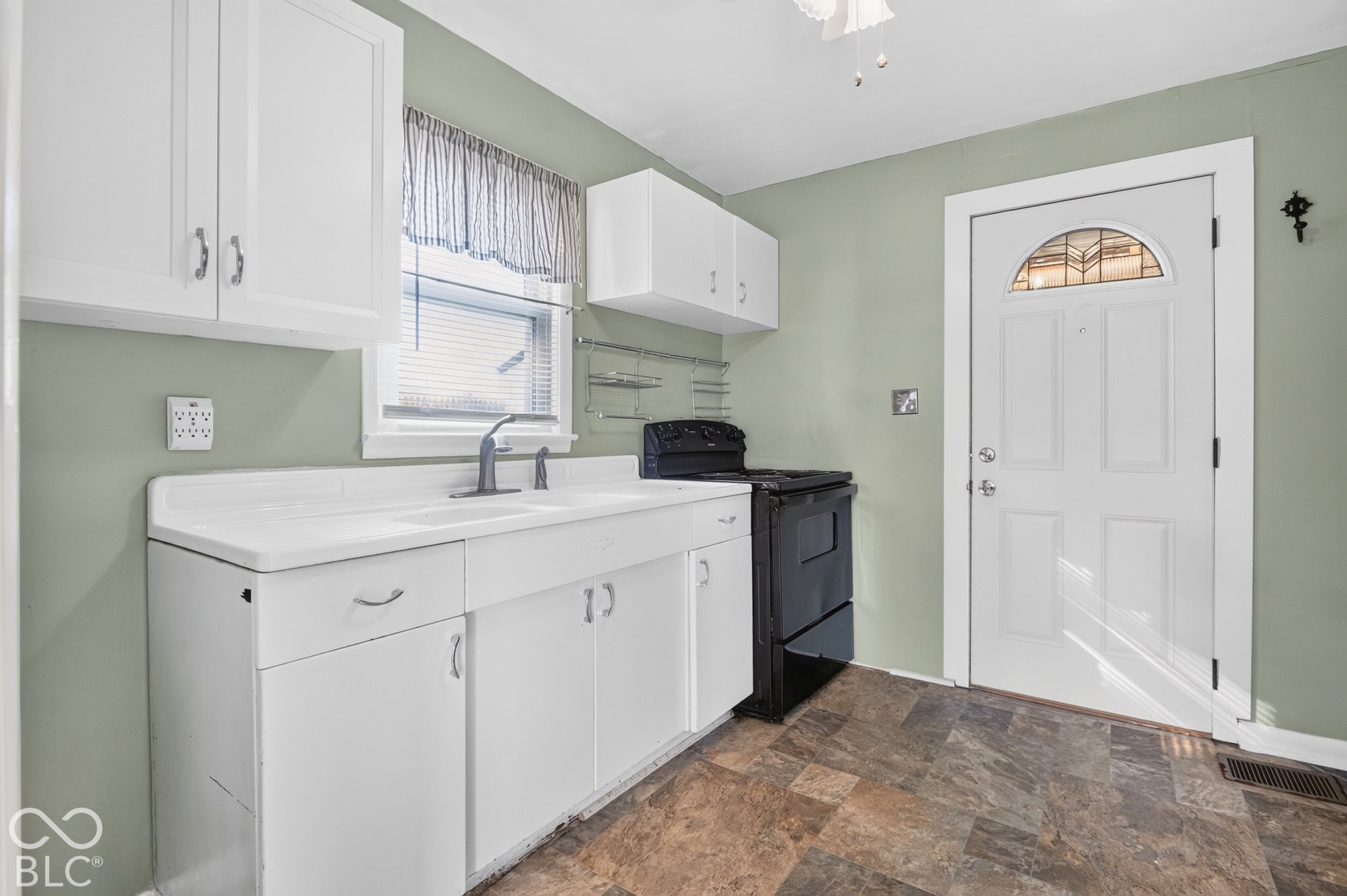 2706 13th Street, Columbus, IN 47201 White cabinetry with integrated sink, black range, multi-toned tile flooring, and exterior door featuring a decorative arched glass insert